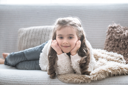 happy little girl lying on the couch, beautiful smile, rest conceptの写真素材