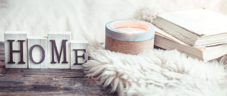 Cozy still life on a wooden background with details in the interior, and wooden letters with the inscription Home and a big beautiful candle, the concept of comfort and home styleの写真素材
