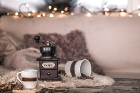 home still life in the interior with an old coffee grinder and a Cup of coffee beans, on the background of a cozy home decor, the concept of coffee at homeの写真素材