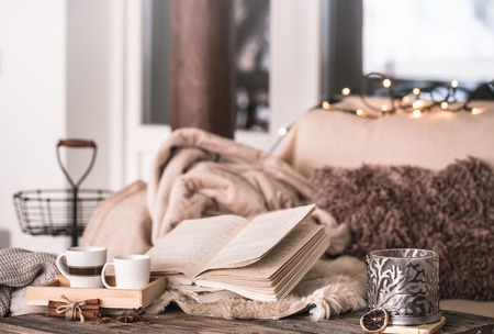 still life home atmosphere in the interior with cups, a book and candles, on the background of cozy bedspreads, home decor elements, the concept of comfort and cozinessの写真素材