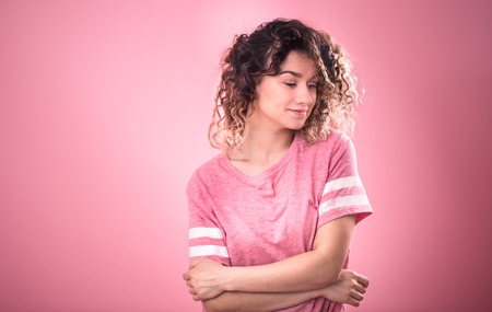 Portrait of beautiful curly girl isolated on pink background, free pink t-shirt ,space for textの写真素材