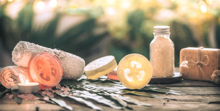 Spa handmade soap with white towels and sea salt, the composition of the tropical leaves with a candle, wooden background with space for text, concept of Spa and relaxation for the bodyの写真素材