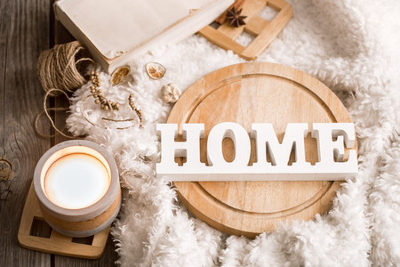 Cozy home decor items with wooden letters, candle and book on the background of beautiful white plaid, home atmosphere conceptの写真素材