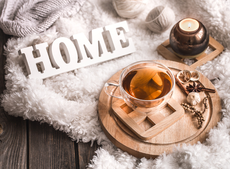 Composition with wooden white letters with the inscription home and a Cup of tea on a wooden background, the concept of home comfortの写真素材