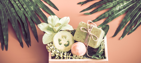 Spa composition with subjects of care of the body in a wooden box on a colored background with a tropical leaf , the concept of Spa and body careの写真素材