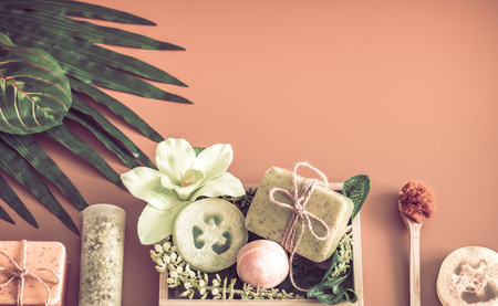 Spa composition with a variety of body care items on a colored background in a wooden box with a tropical leaf, Spa and body care conceptの写真素材