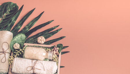 Spa composition with a variety of body care items on a colored background in a wooden box with a tropical leaf, Spa and body care conceptの写真素材