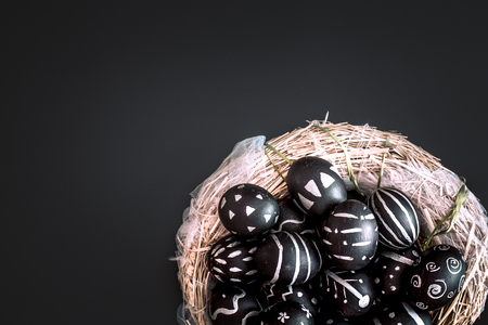 Easter eggs black and white pattern handmade in a nest of hay isolated on a black background, the concept of the Easter holidaysの写真素材