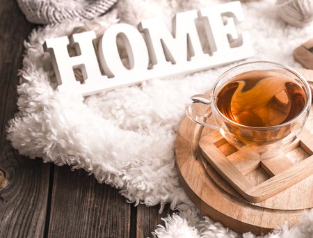 Composition with wooden white letters with the inscription home and a Cup of tea on a wooden background, the concept of home comfortの写真素材