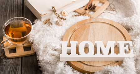 Composition with wooden white letters with the inscription home and a Cup of tea on a wooden background, the concept of home comfortの写真素材