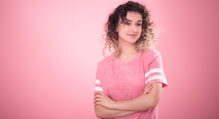 Portrait of beautiful curly girl isolated on pink background, free pink t-shirt ,space for textの写真素材