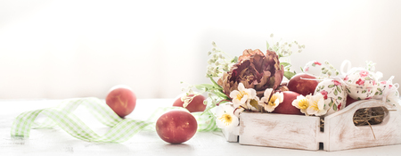 Easter background with a basket and red eggs with flowers, the bright interior, the concept of the Easter holidaysの写真素材