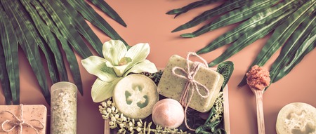 Spa composition with a variety of body care items on a colored background in a wooden box with a tropical leaf, Spa and body care conceptの写真素材