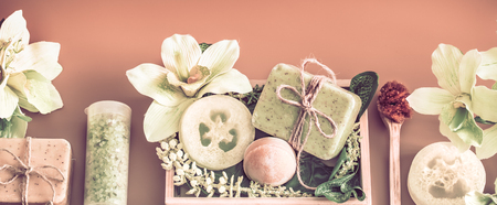 Spa composition with a variety of body care items on a colored background in a wooden box with a tropical leaf, Spa and body care conceptの写真素材