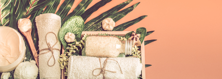 Spa composition with a variety of body care items on a colored background in a wooden box with a tropical leaf, Spa and body care conceptの写真素材
