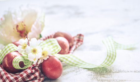 Easter background with a basket and red eggs with flowers, the bright interior, the concept of the Easter holidaysの写真素材