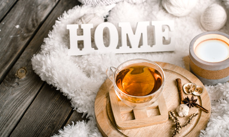 Composition with wooden white letters with the inscription home and a Cup of tea on a wooden background, the concept of home comfortの写真素材