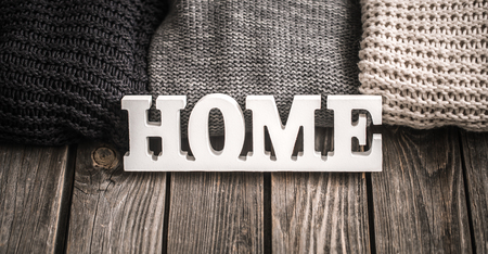 wooden decorative large white letters with home lettering and knitted sweaters white, gray and black on wooden backgroundの写真素材