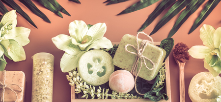 Spa composition with a variety of body care items on a colored background in a wooden box with a tropical leaf, Spa and body care conceptの写真素材
