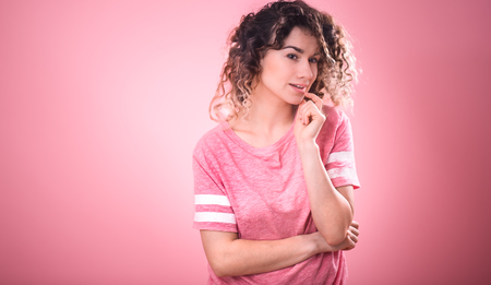 Portrait of beautiful curly girl isolated on pink background, free pink t-shirt ,space for textの写真素材