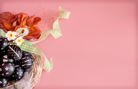 Easter composition from eggs of the black colors with creative light pattern, handmade in a round nest of hay isolated on a pink background , the concept of the Easter holidaysの写真素材