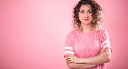 Portrait of beautiful curly girl isolated on pink background, free pink t-shirt ,space for textの写真素材