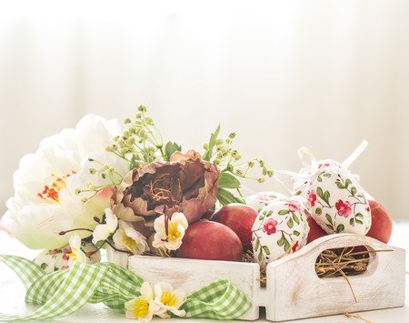 Easter background with a basket and red eggs with flowers, the bright interior, the concept of the Easter holidaysの写真素材