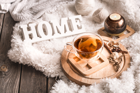 Composition with wooden white letters with the inscription home and a Cup of tea on a wooden background, the concept of home comfortの写真素材