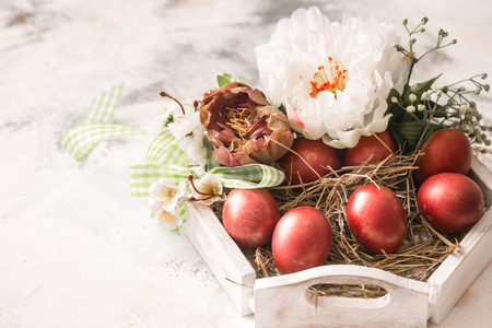 Easter background with a basket and red eggs with flowers, the bright interior, the concept of the Easter holidaysの写真素材