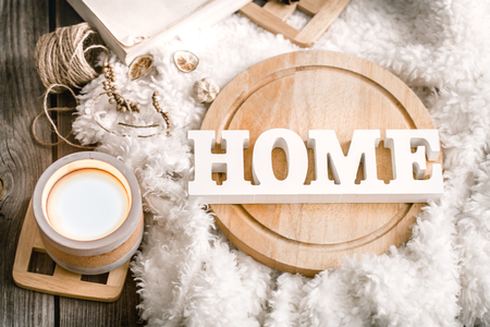 Cozy home decor items with wooden letters, candle and book on the background of beautiful white plaid, home atmosphere conceptの写真素材