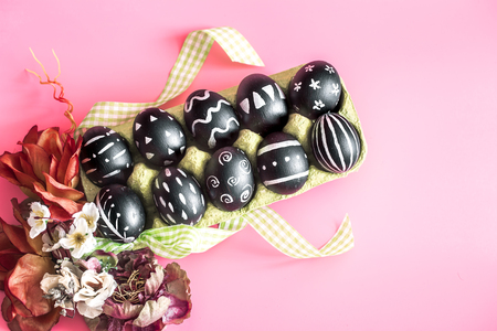 Easter composition from eggs of the black colors with creative light pattern, handmade in a round nest of hay isolated on a pink background , the concept of the Easter holidaysの写真素材