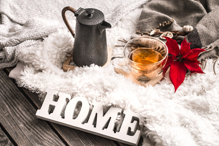 Composition with wooden white letters with the inscription home and a Cup of tea and a kettle on a wooden background, the concept of home comfortの写真素材