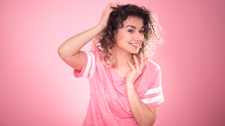 Portrait of beautiful curly girl isolated on pink background, free pink t-shirt ,space for textの写真素材