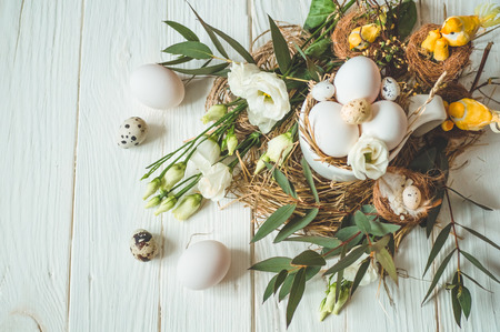 Happy Easter background. Easter eggs in a cup on a wooden white background with floral decoration. Quail eggs. Happy Easter conceptの写真素材
