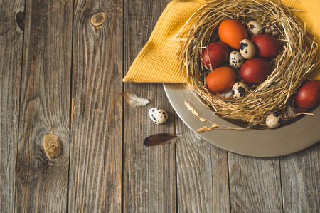 Happy Easter background. Easter eggs in a nest on a metal plate on a wooden background. Quail eggs. Happy Easter conceptの写真素材