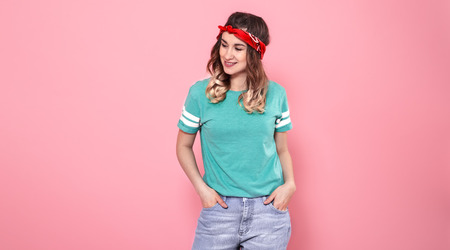 Horizontal portrait of Caucasian girl hipster in stylish clothes with a bright T-shirt and a red bandage, isolated on a pink background, lifestyle conceptの写真素材