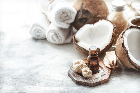 still life with coconut oil in a bottle and fresh coconut on a light background, spa therapy conceptの写真素材