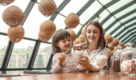 Happy young women mother with children sitting at the table and drinking a milkshake in a restaurant or cafe. In Leisure and communication with children restaurant. The concept of familyの写真素材