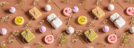 Flat composition with cosmetic products on a colored background. Spring flowers, soap, bath bomb. View from the top banner. Place for textの写真素材