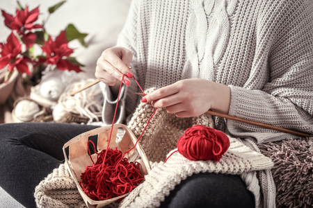 wooden spokes and red yarn in the hands of a woman on a cozy sofa . Still life photo. The concept of comfortの写真素材
