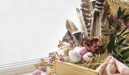 Happy Easter background. Pink Easter eggs in a nest with floral decorations and feathers near the window. Quail eggs. Happy Easter concept.の写真素材