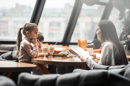 Happy young women mother with children sitting at dinner table and talking in restaurant or cafe. In Leisure and communication with children restaurantの写真素材