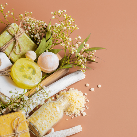 Top view of spa and body care accessories in wooden box on colored background. With soap, leaves, flowers, bath bombs and body and face accessoriesの写真素材