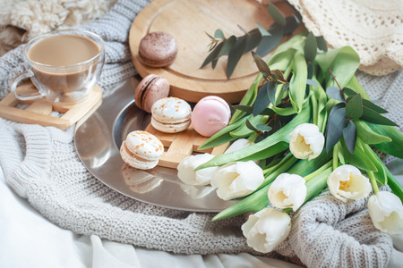 Still-life morning breakfast with coffee and macaroon on the background of a bed with white tulips, concept of women's dayの写真素材