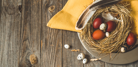 Happy Easter background. Easter eggs in a nest on a metal plate on a wooden background. Quail eggs. Happy Easter conceptの写真素材