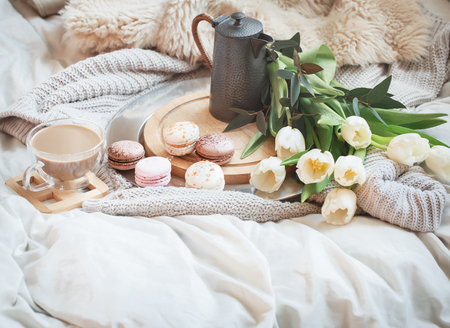 Still-life morning breakfast with coffee and macaroon on the background of a bed with white tulips, concept of women's dayの写真素材