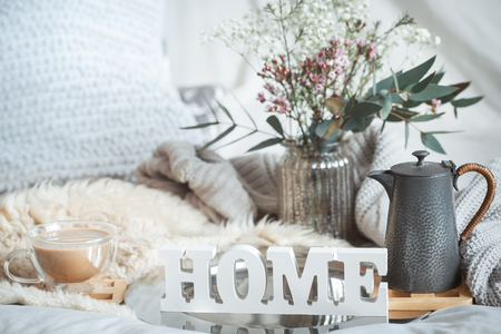 Home spring still life with a cup of coffee and a teapot on the background of the bed and a wooden inscription homeの写真素材