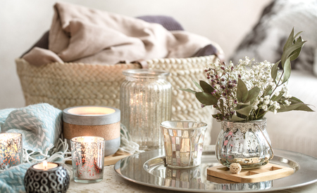 Home decorations in the interior. On the wooden background lies a turquoise blanket and wicker basket with a vase of flowers and candles. Concept of comfortの写真素材