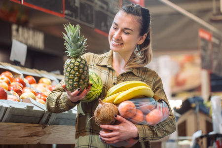Woman in the supermarket. Beautiful young woman shopping in a supermarket and buying fresh organic vegetables. The concept of healthy eating. Harvestの写真素材