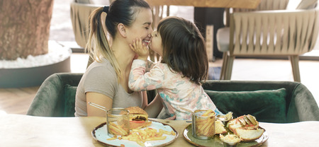 Loving family. Mom with cute daughter eating fast food in a cafe, family and nutrition conceptの写真素材
